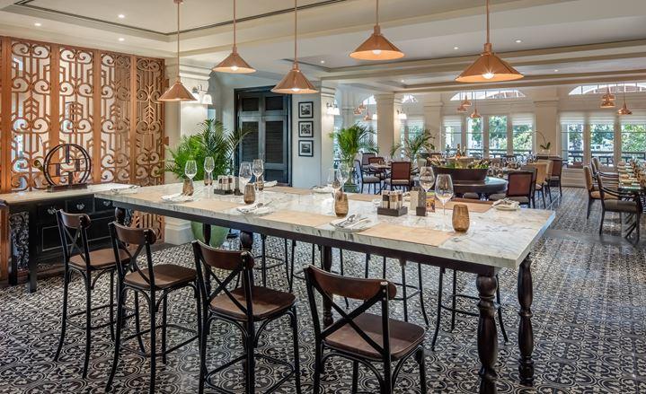 a large table with wine glasses and chairs in a room with a large wall