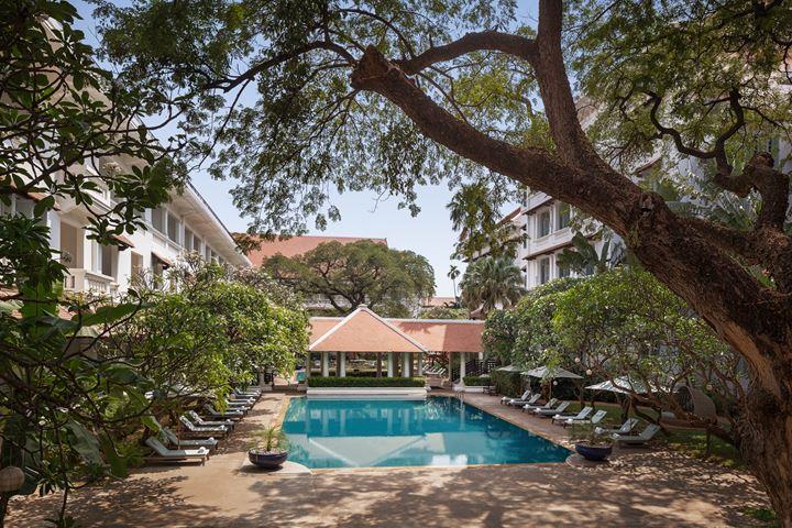 a swimming pool with lounge chairs and trees around it