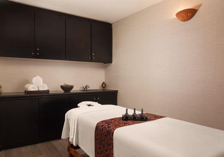 a massage room with a white bed and black cabinets
