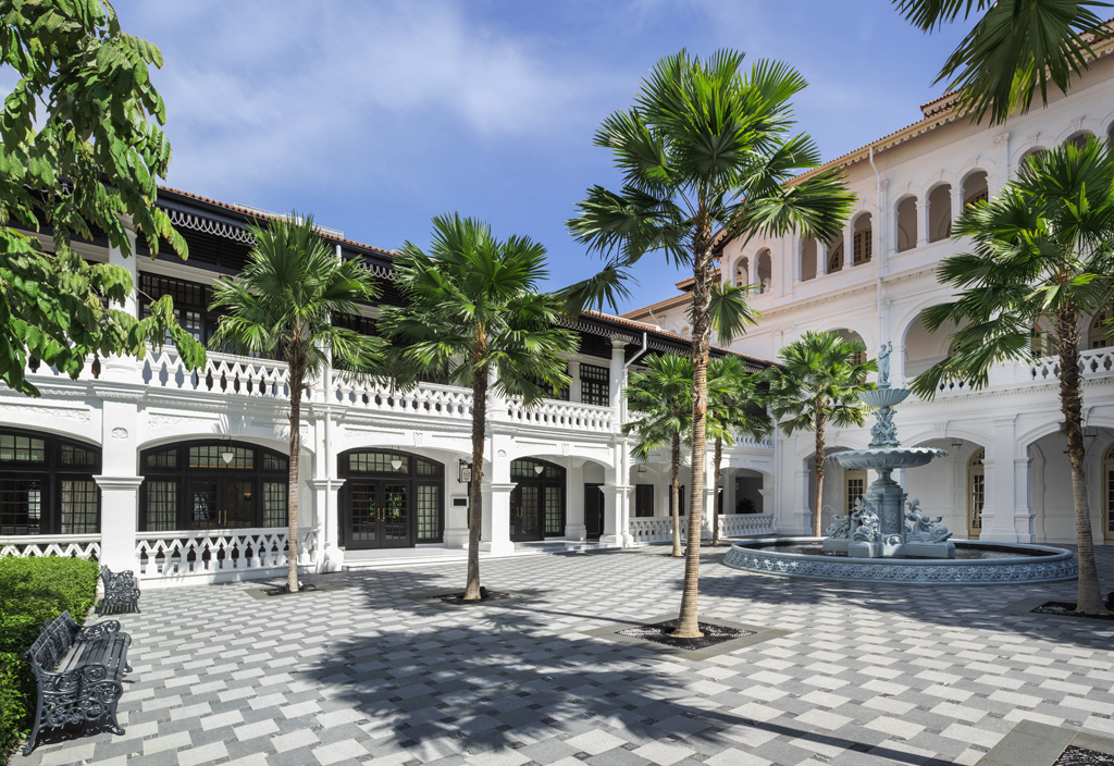 a courtyard with palm trees and a fountain with Star Island in the background