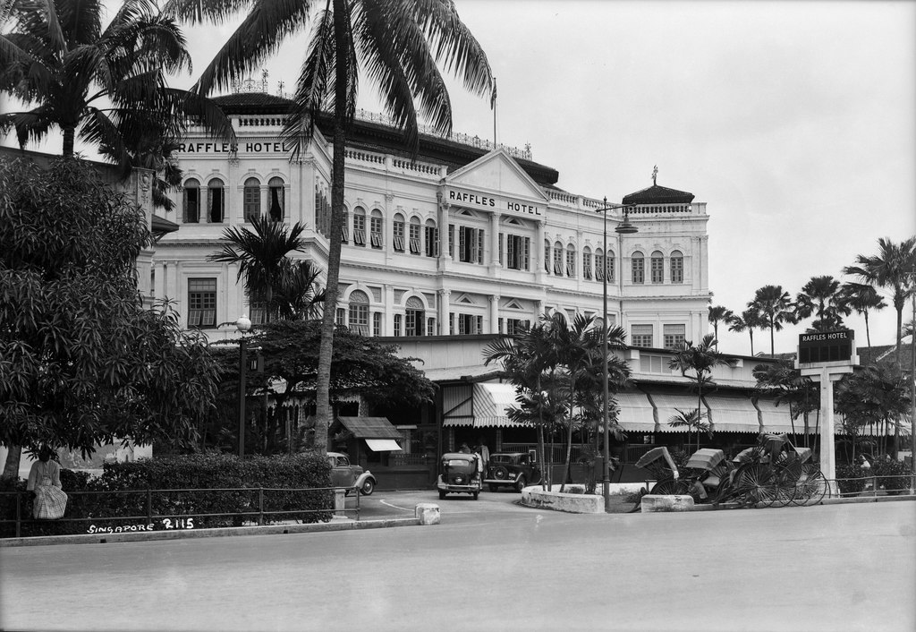 a large white building with palm trees and cars