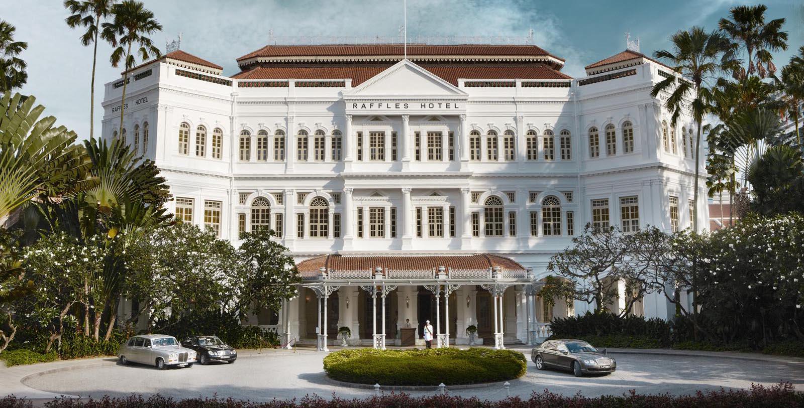 a white building with cars parked in front of it with Raffles Hotel in the background