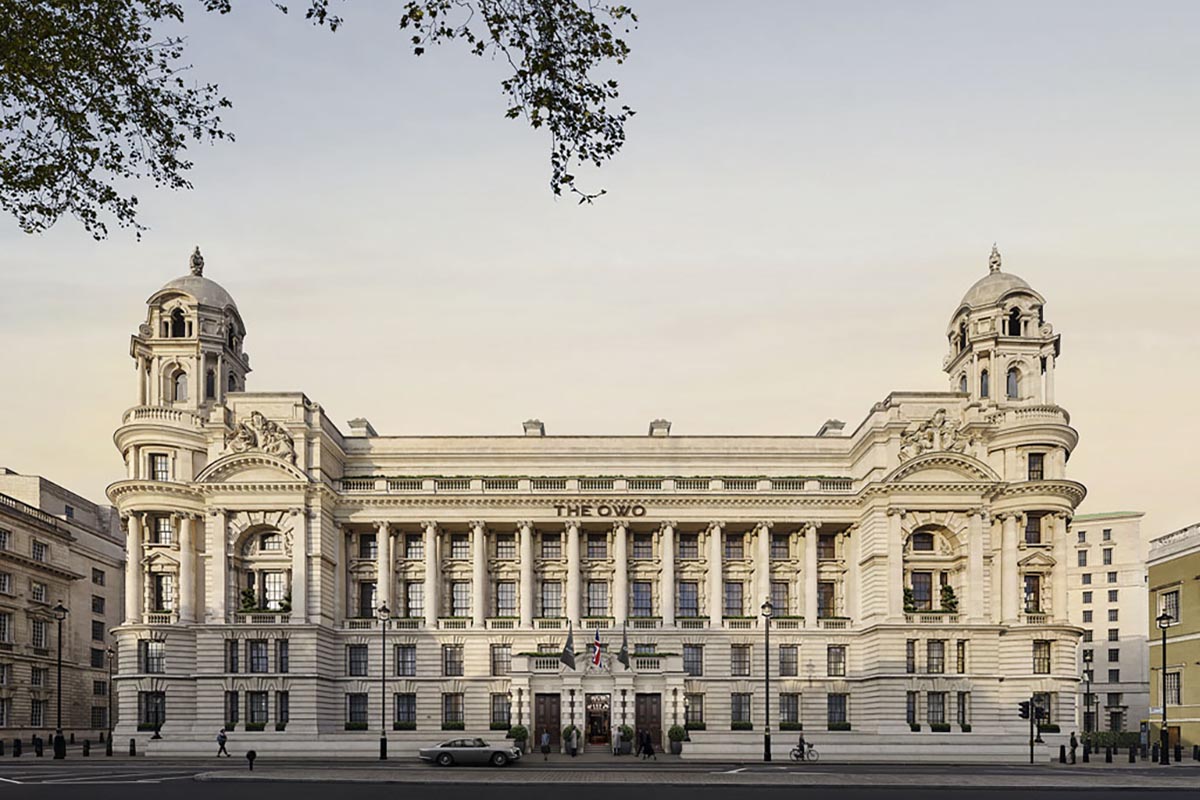 a large white building with columns and a couple of cars parked on the street