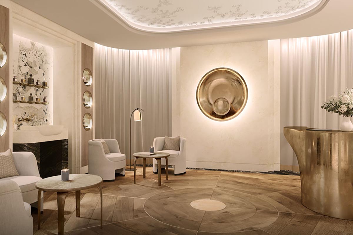 A luxurious spa or hotel reception lobby featuring elegant light-toned armchairs, wooden coffee tables, warm ambient lighting, soft flowing curtains, a polished brass reception counter, and a circular wall art installation.