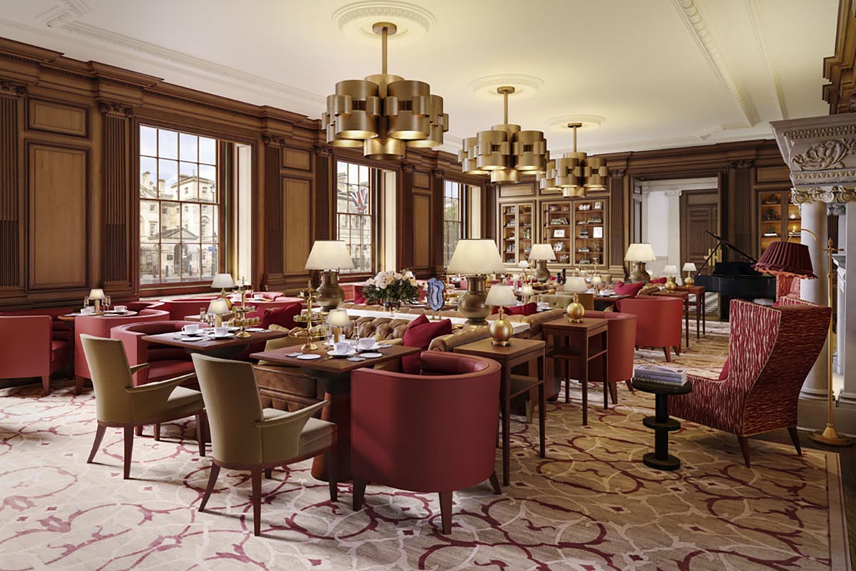A lavish hotel lounge or dining room featuring rich wood wall paneling, large brass chandelier light fixtures, red leather armchairs, patterned carpeting, and set tables illuminated by individual lamps.