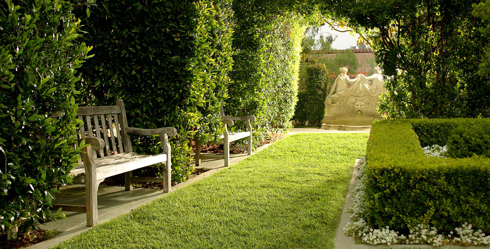 a garden with a statue and a bench