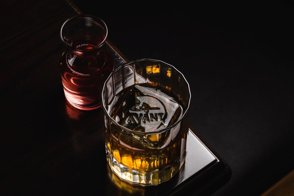 a glass of liquid next to a bottle