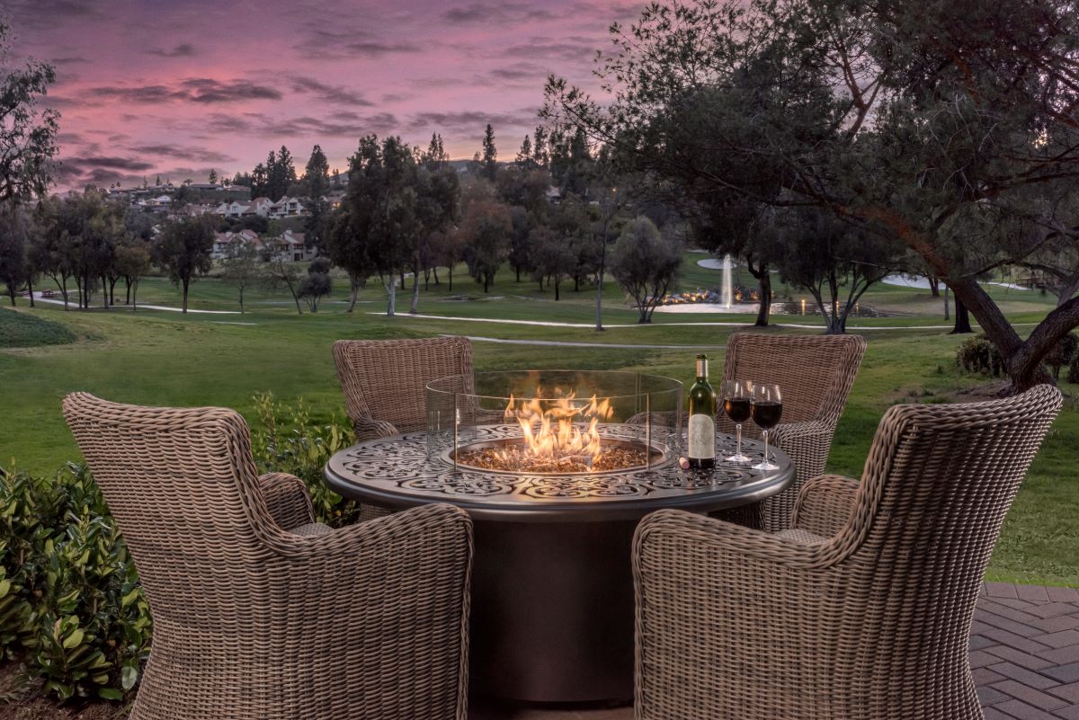 a table with wine bottles and a fire pit in front of a golf course
