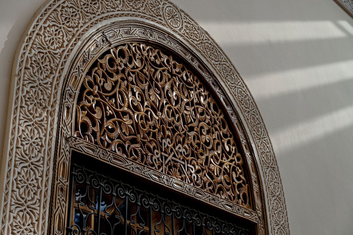 a ornate arched window with a metal grill
