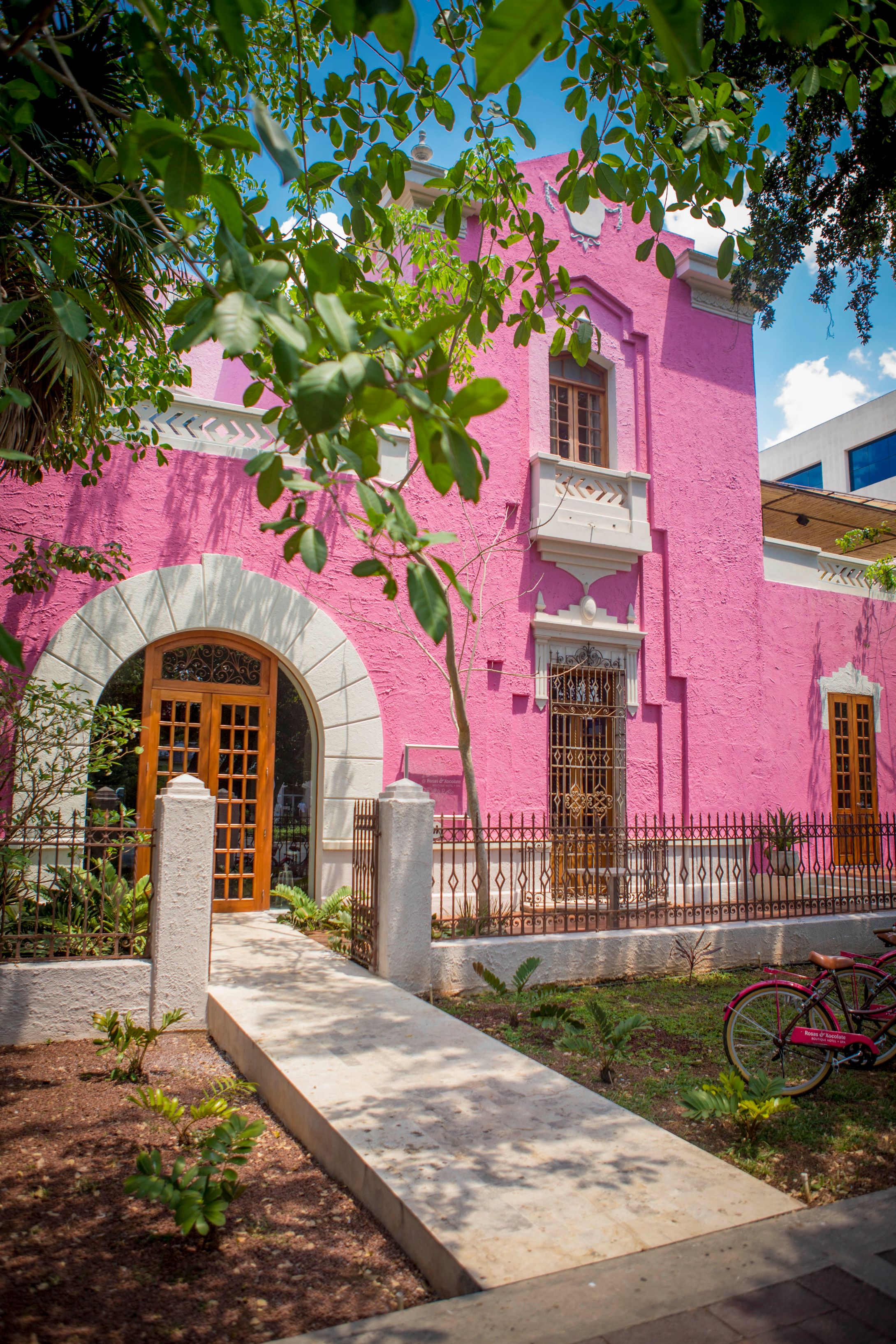 a pink building with a fence and a bicycle