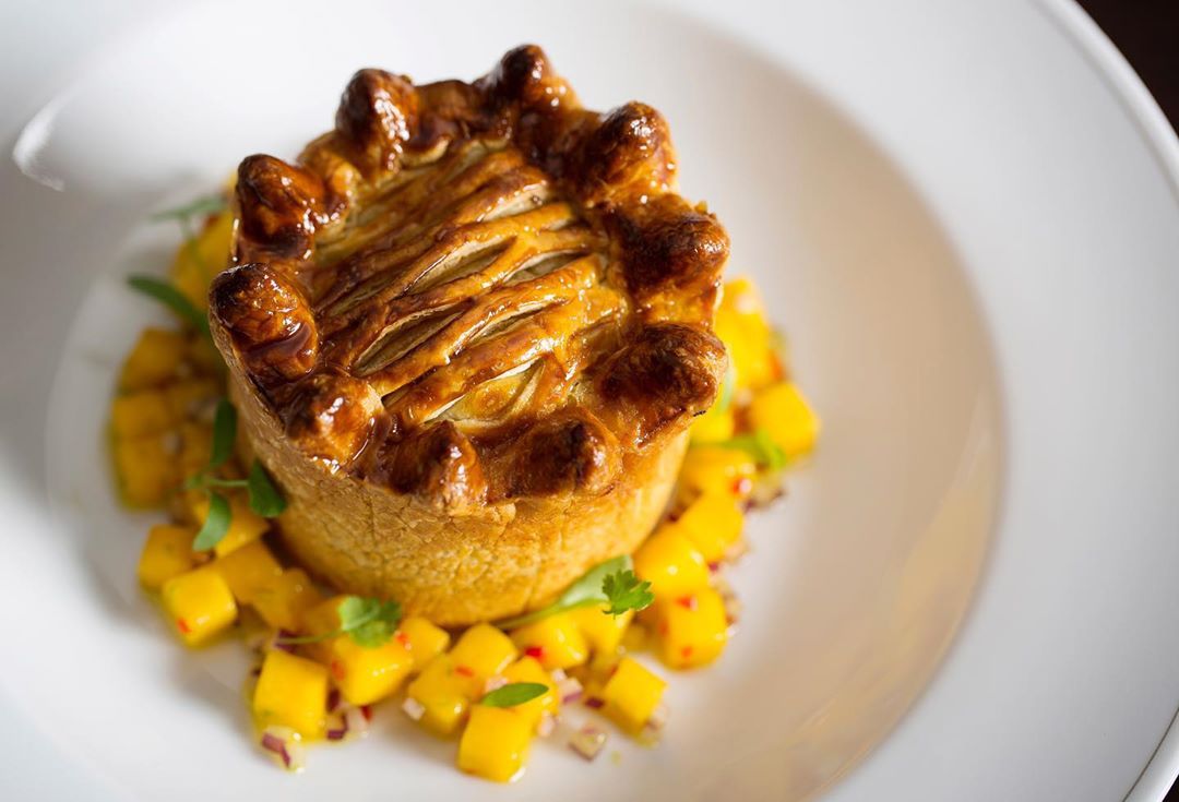 a pie with a mango topping on a white plate