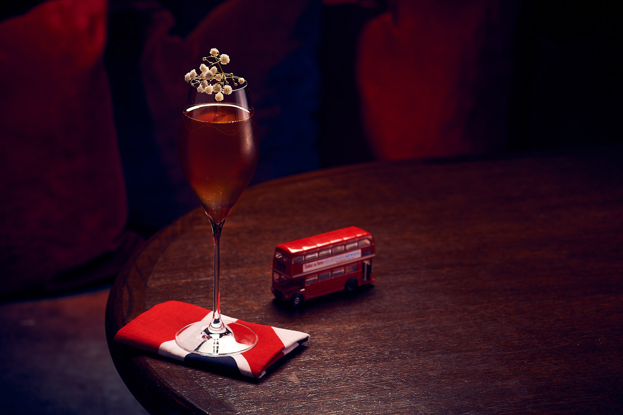 a glass of wine with a flower on top of it next to a toy bus