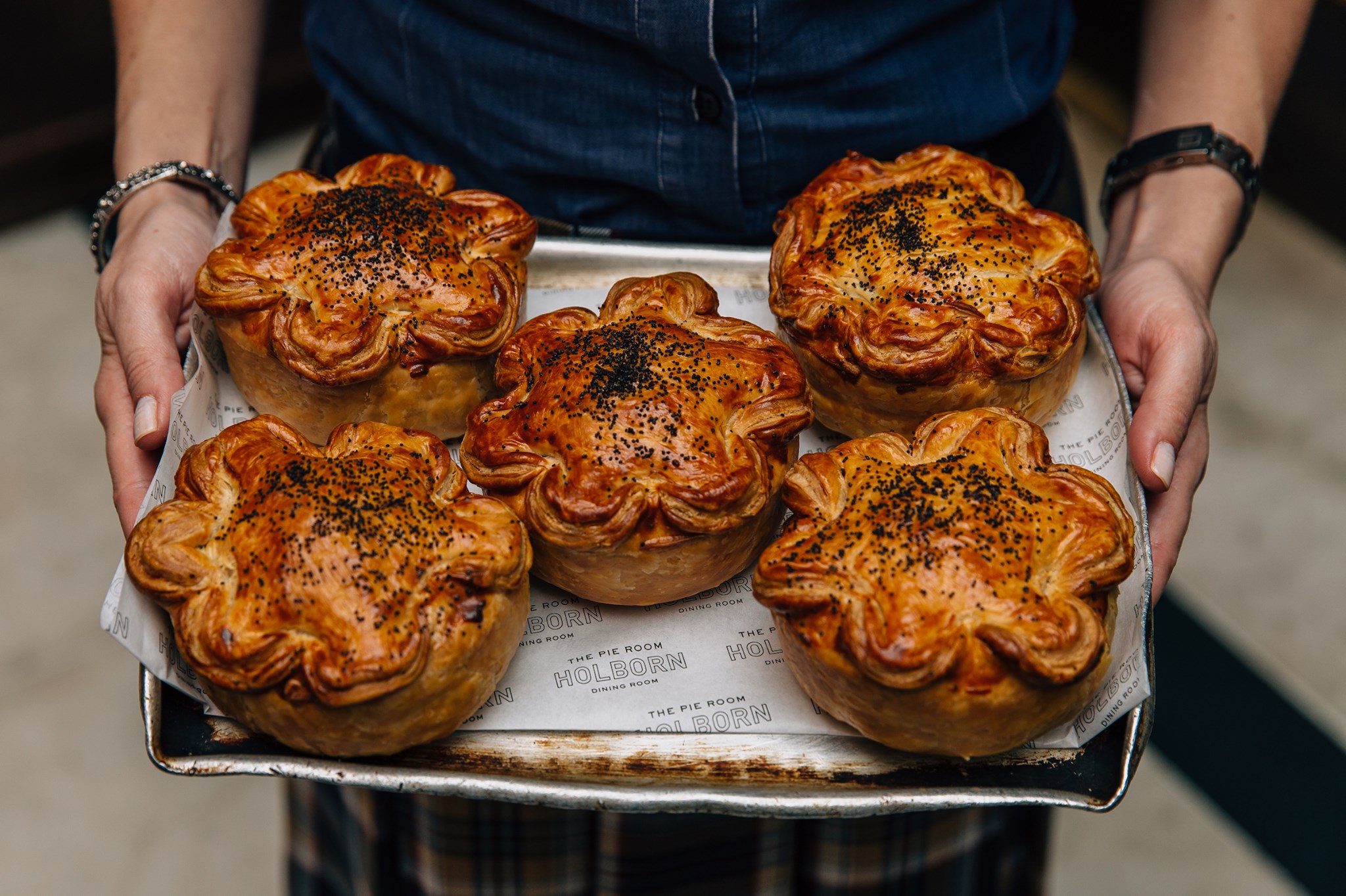 a person holding a tray of baked food