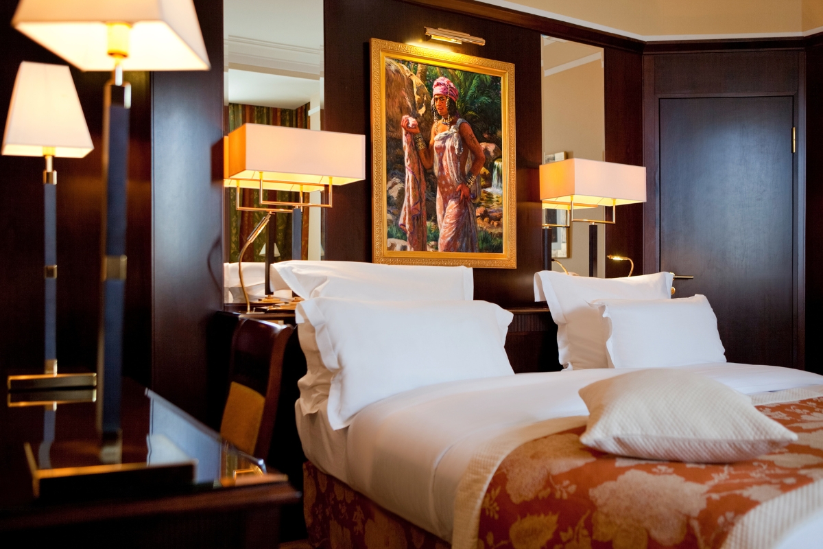 a bed with white pillows and a painting on the wall