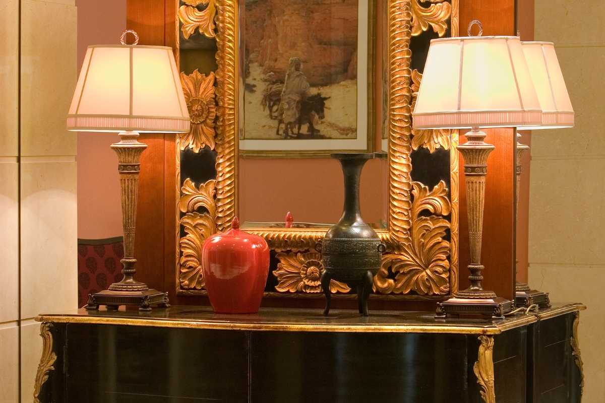 a mirror with a vase and lamps on a table