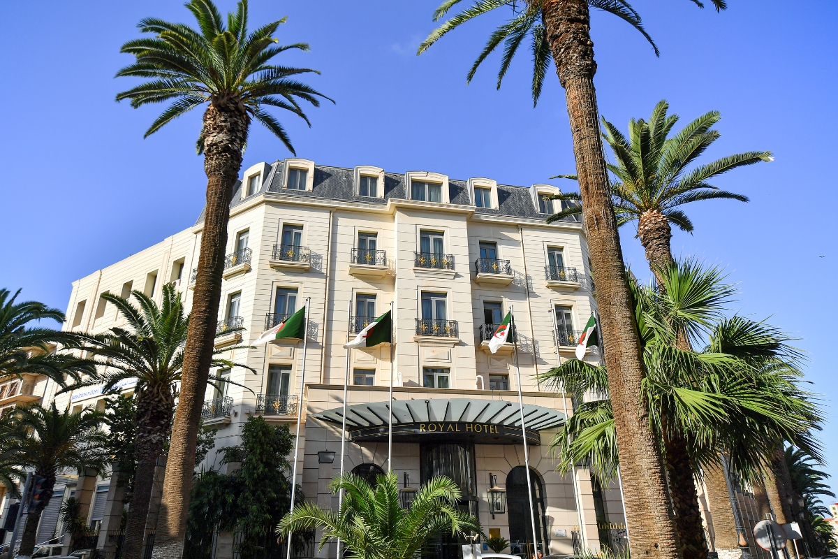 a building with palm trees and flags