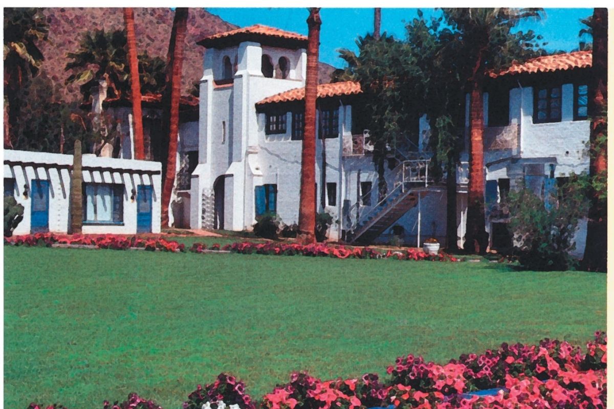 a green lawn with flowers in front of a white building