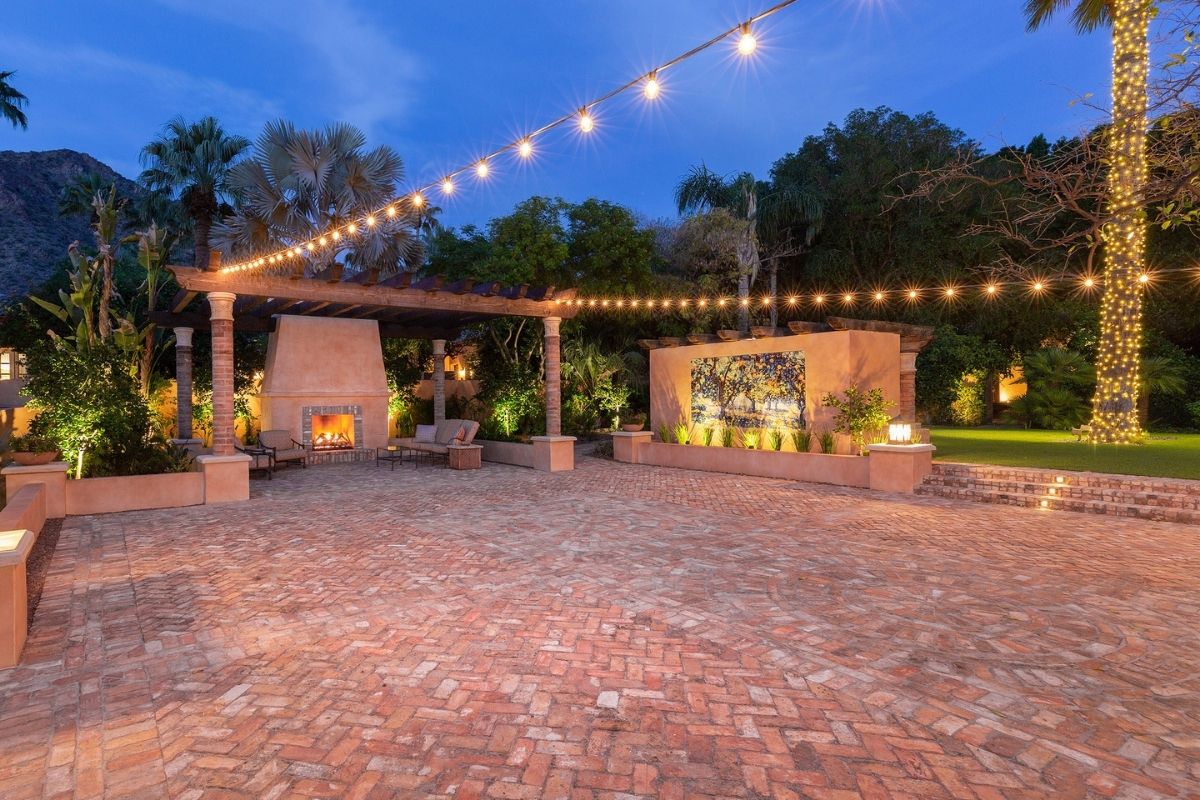 a brick patio with a fire place and lights