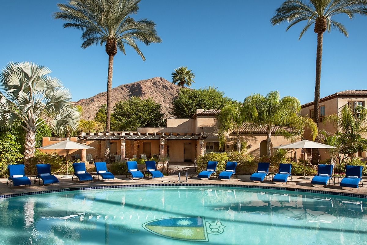 a pool with chairs and umbrellas in front of a building