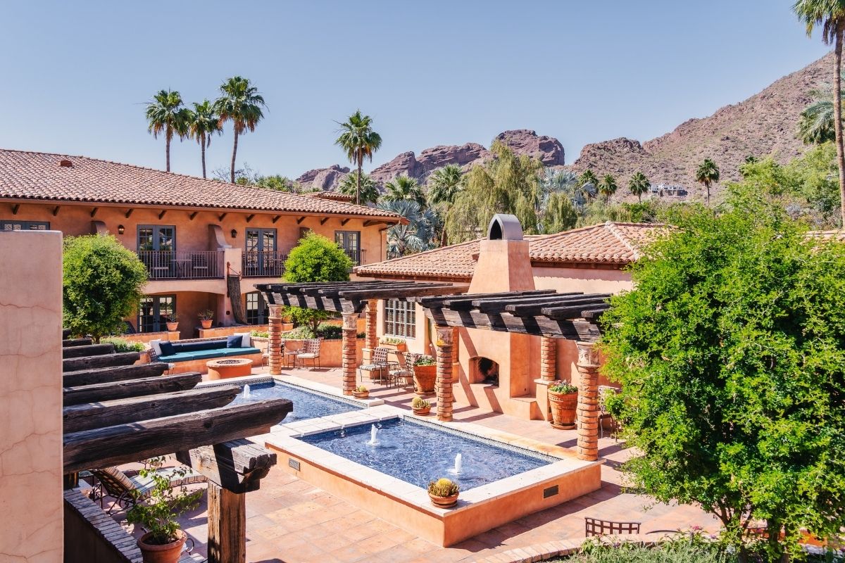 a pool and a building with trees and mountains in the background