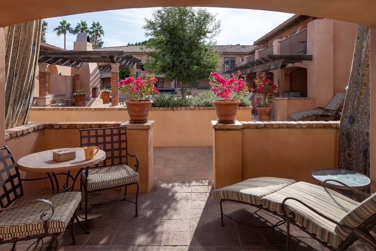 a patio with chairs and tables and flowers