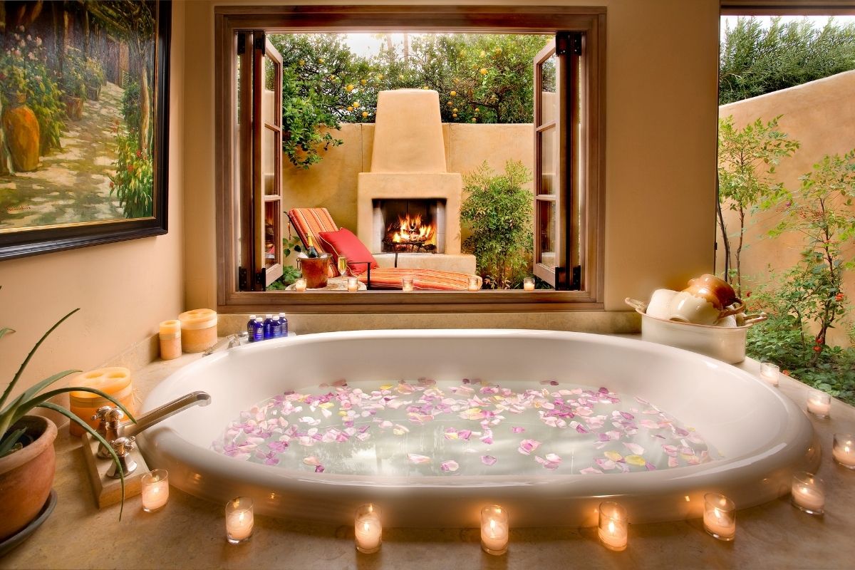 a bathtub with candles and flowers in it