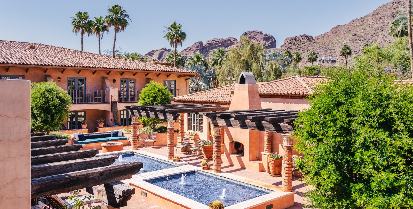 a pool and a building with trees and mountains in the background