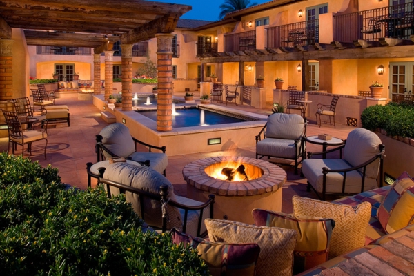 a patio with a fire pit and chairs