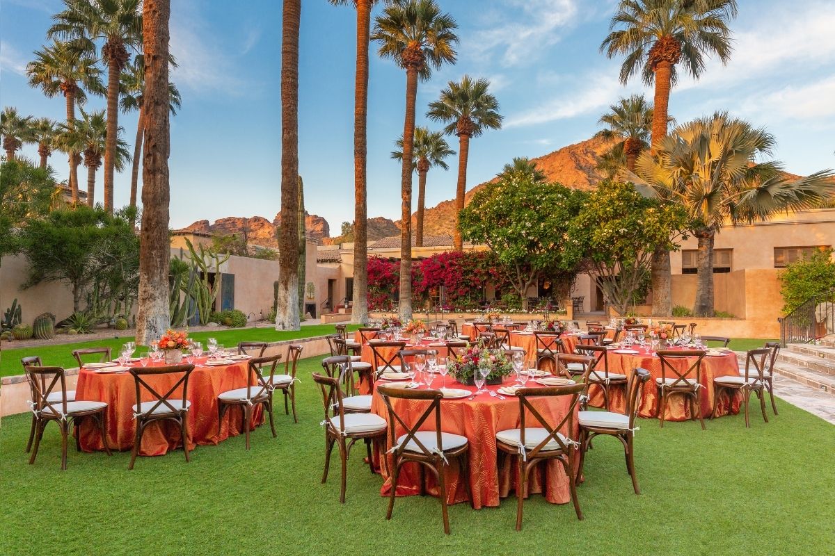a group of tables set up in a grassy area with palm trees