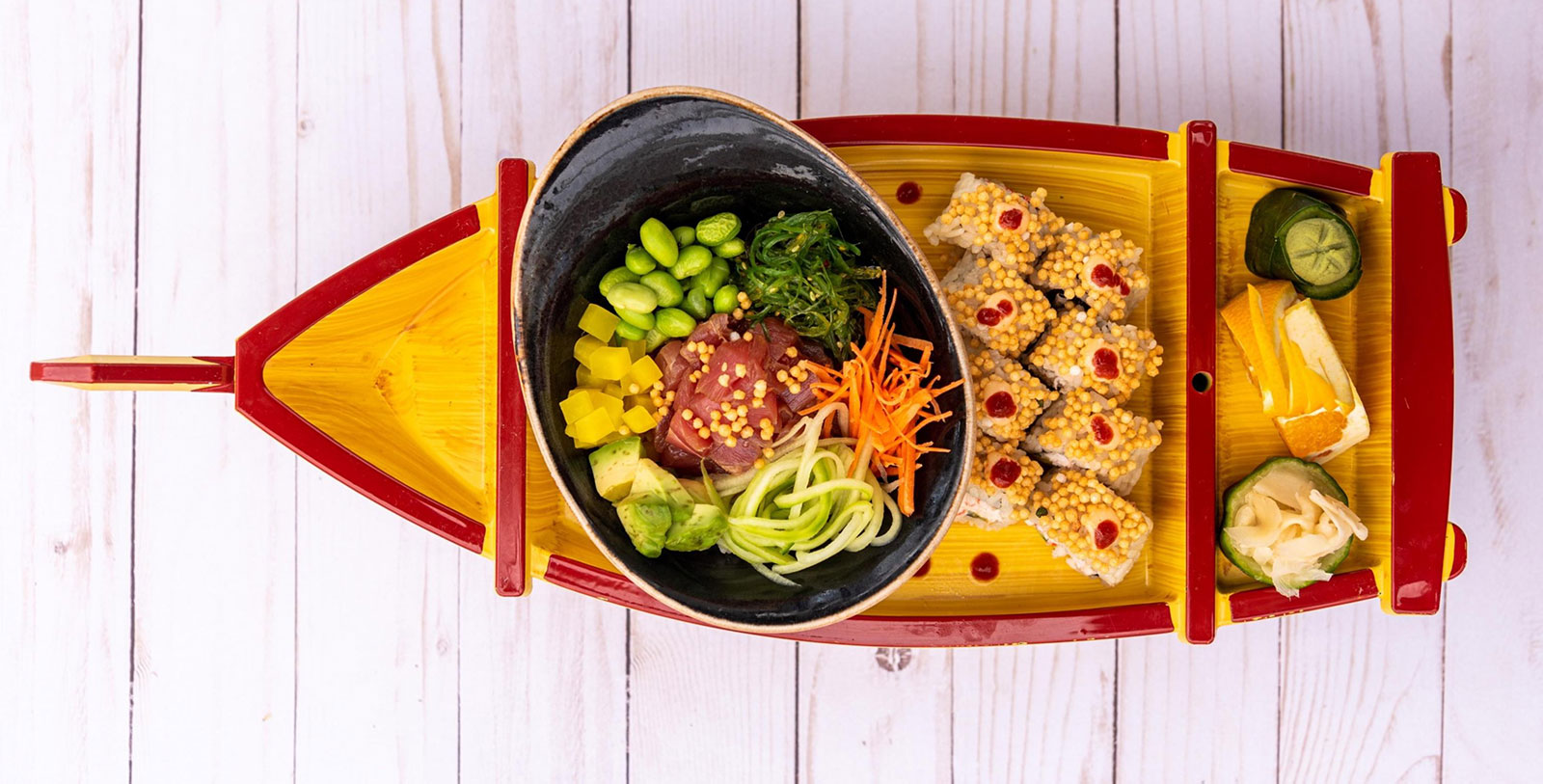 a bowl of sushi and sushi rolls on a boat