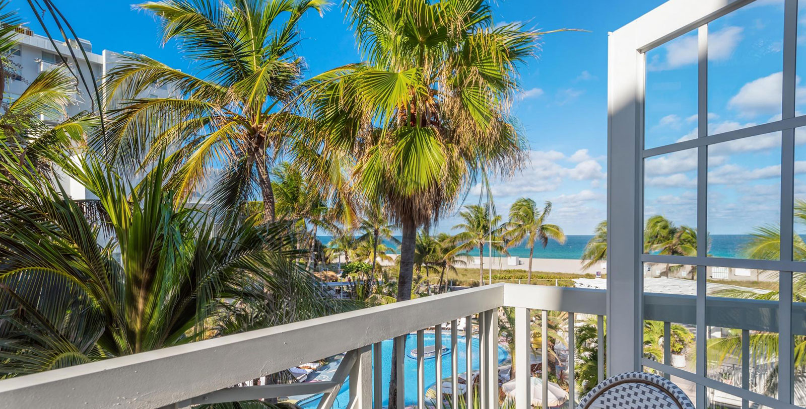 a balcony with palm trees and a pool