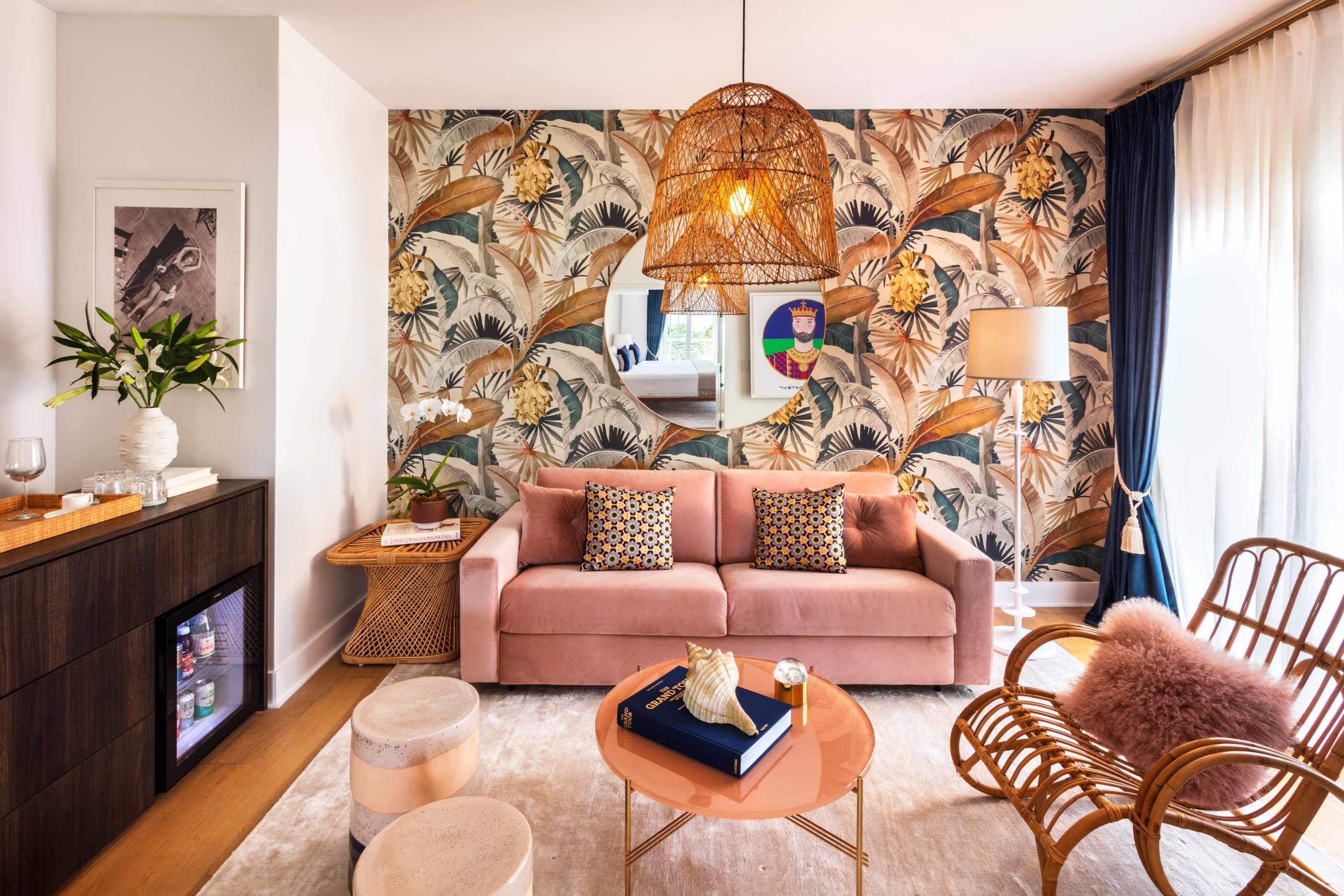 a living room with a pink couch and a round mirror