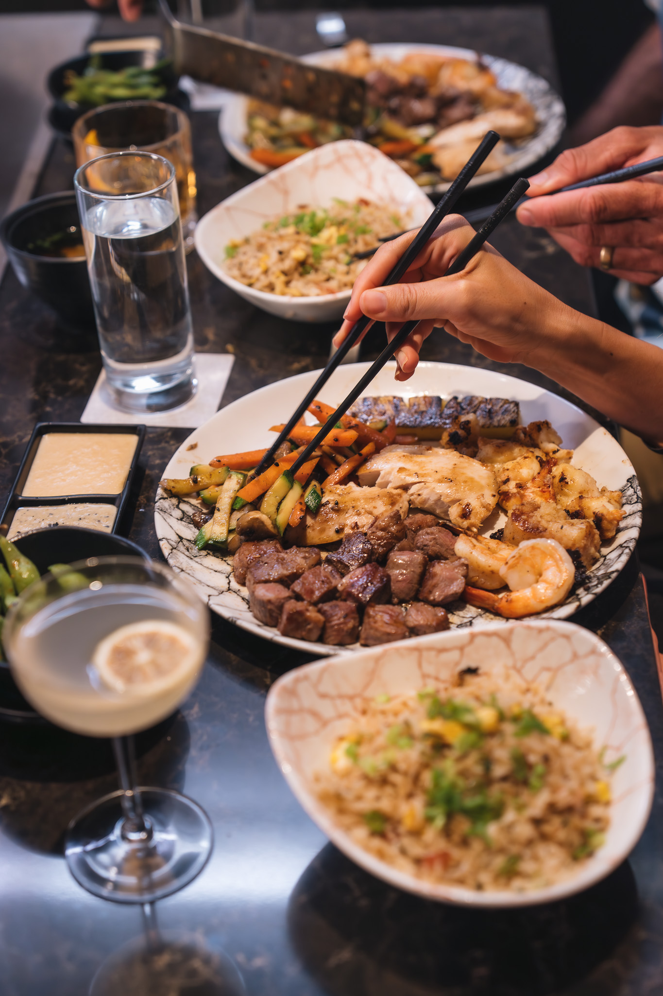 a person holding chopsticks over a plate of food