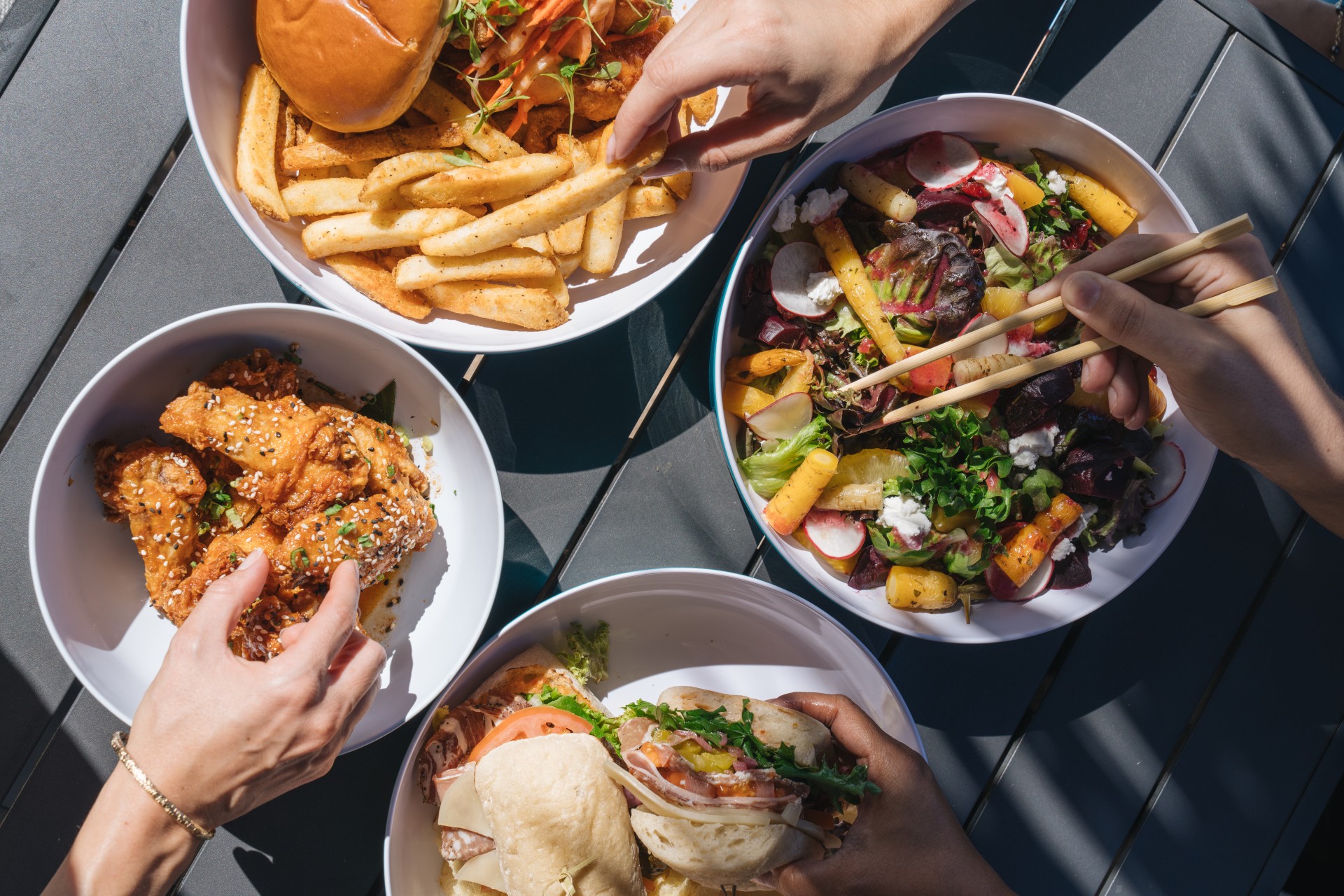 a group of hands holding food in bowls
