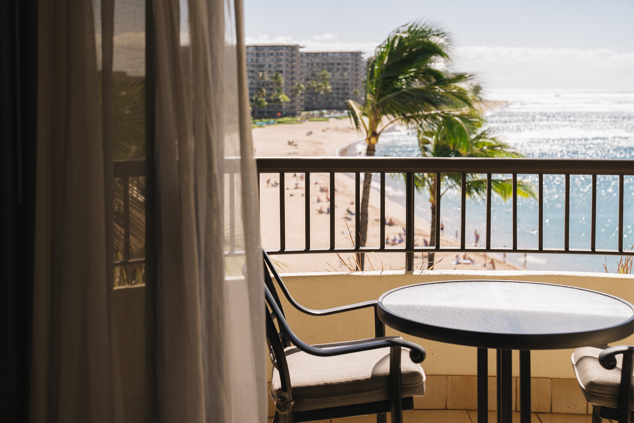 a table and chair on a balcony overlooking a beach