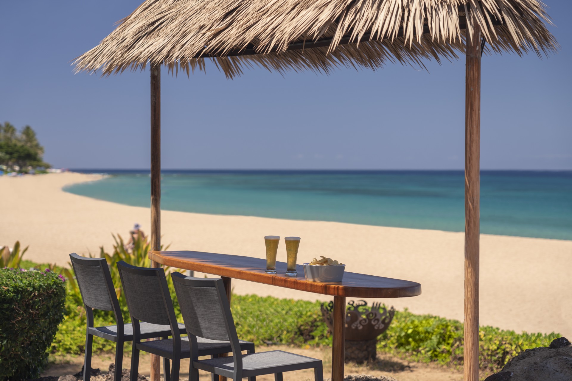 a table with drinks on it and chairs on a beach