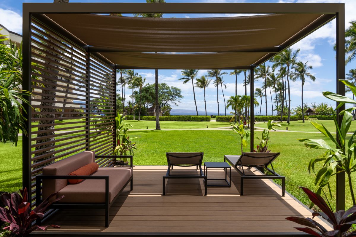 a patio with a covered area and a lawn and palm trees