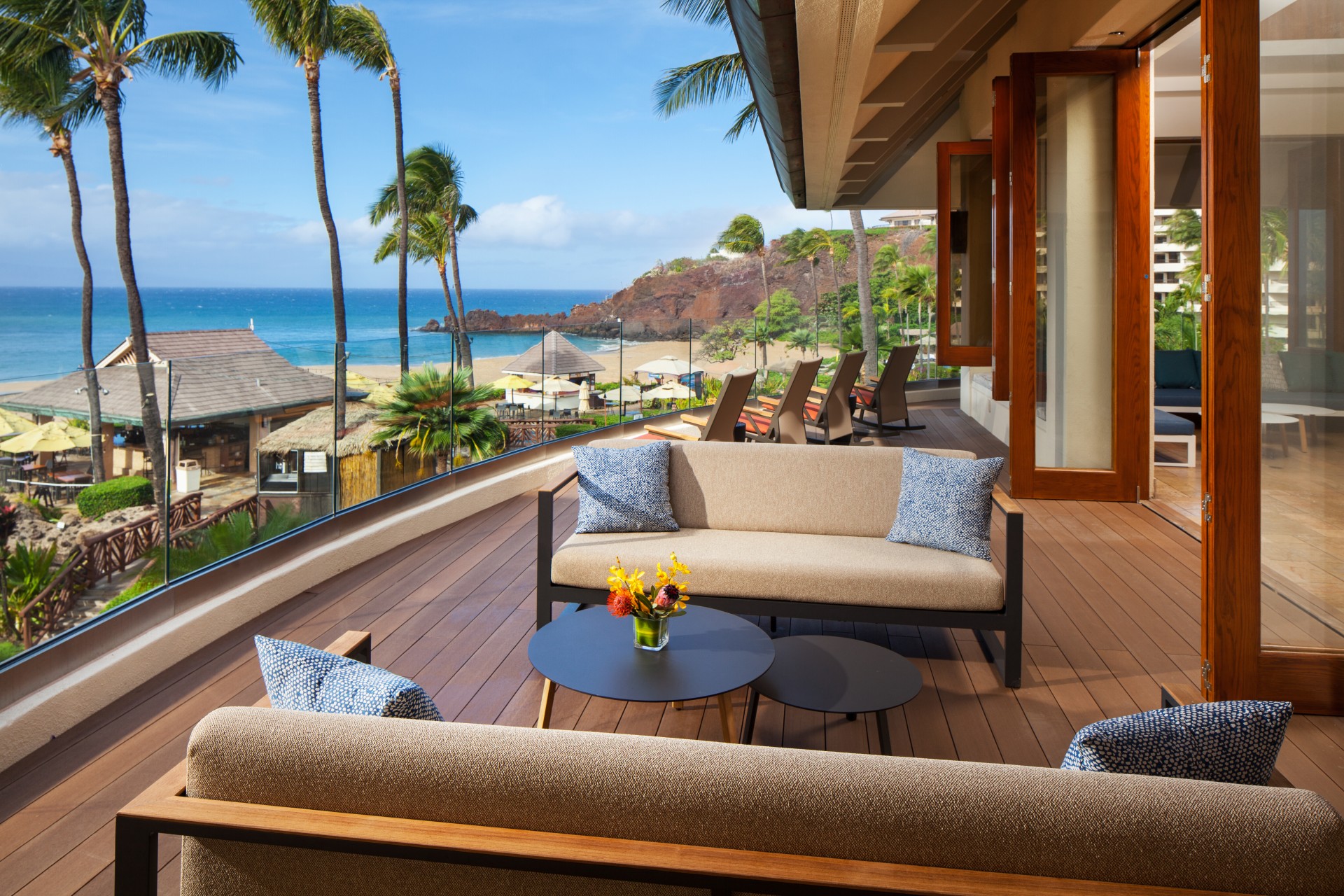a patio with a view of the ocean and palm trees