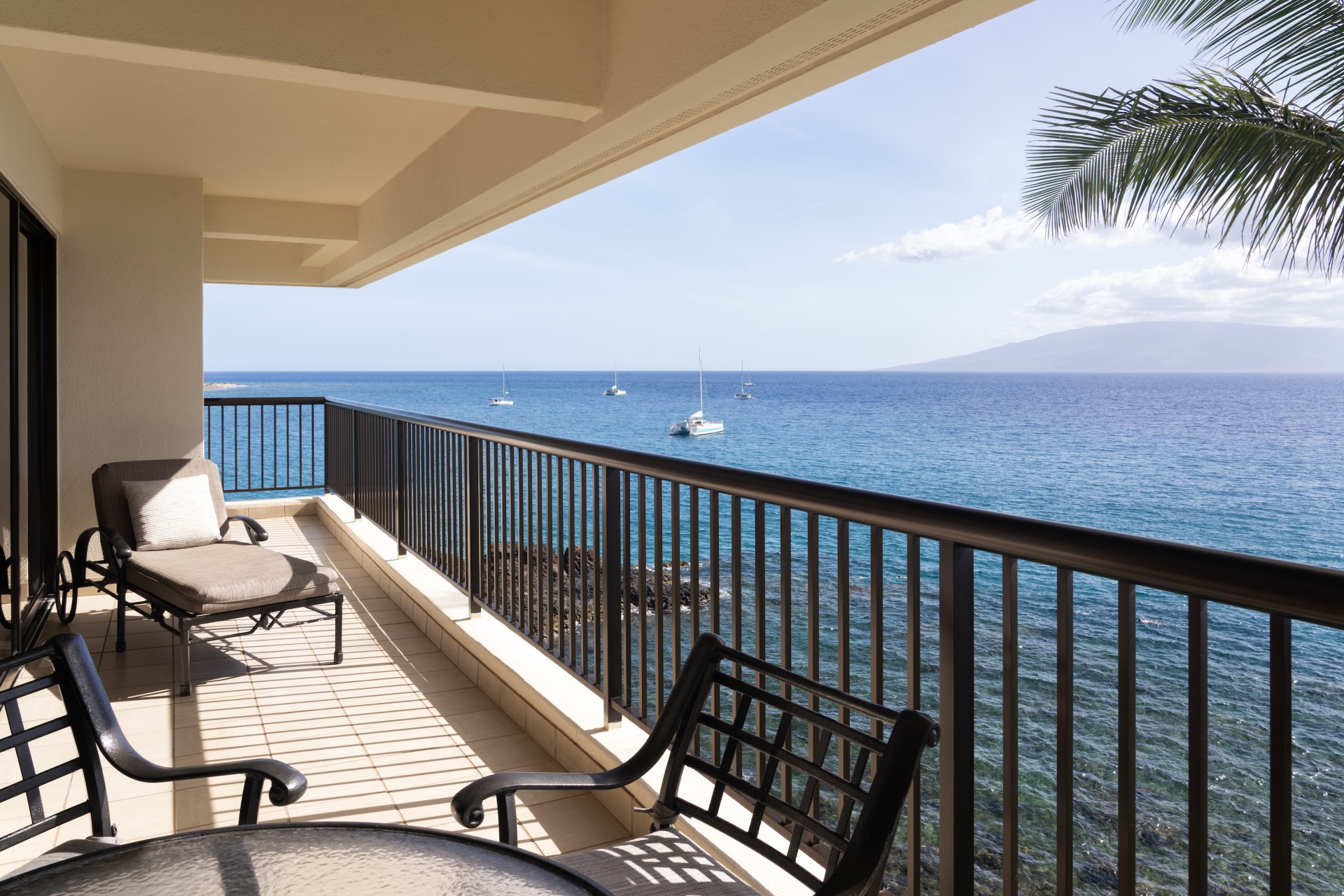 a deck with chairs and a railing overlooking the ocean