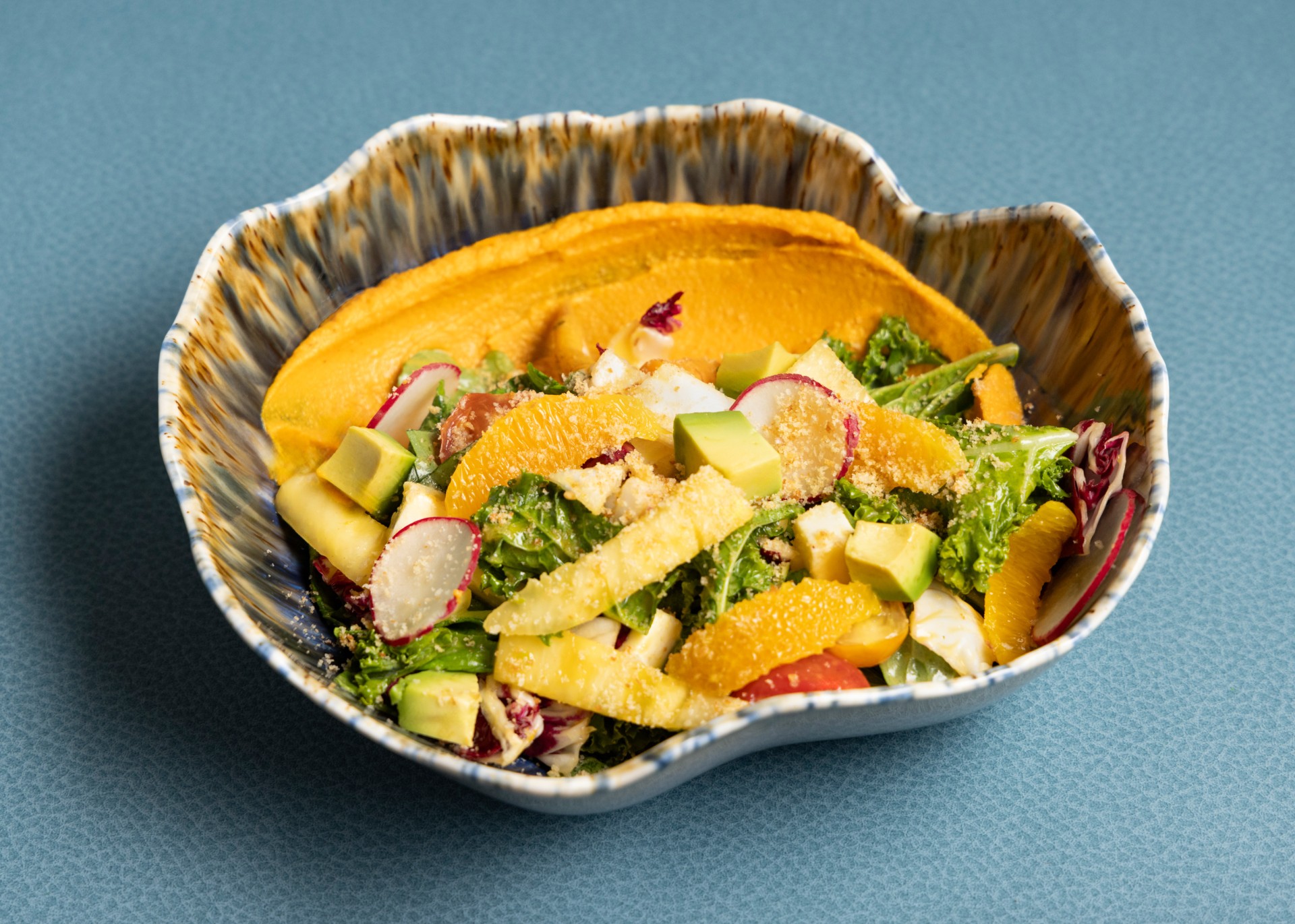 a bowl of salad with oranges and avocado