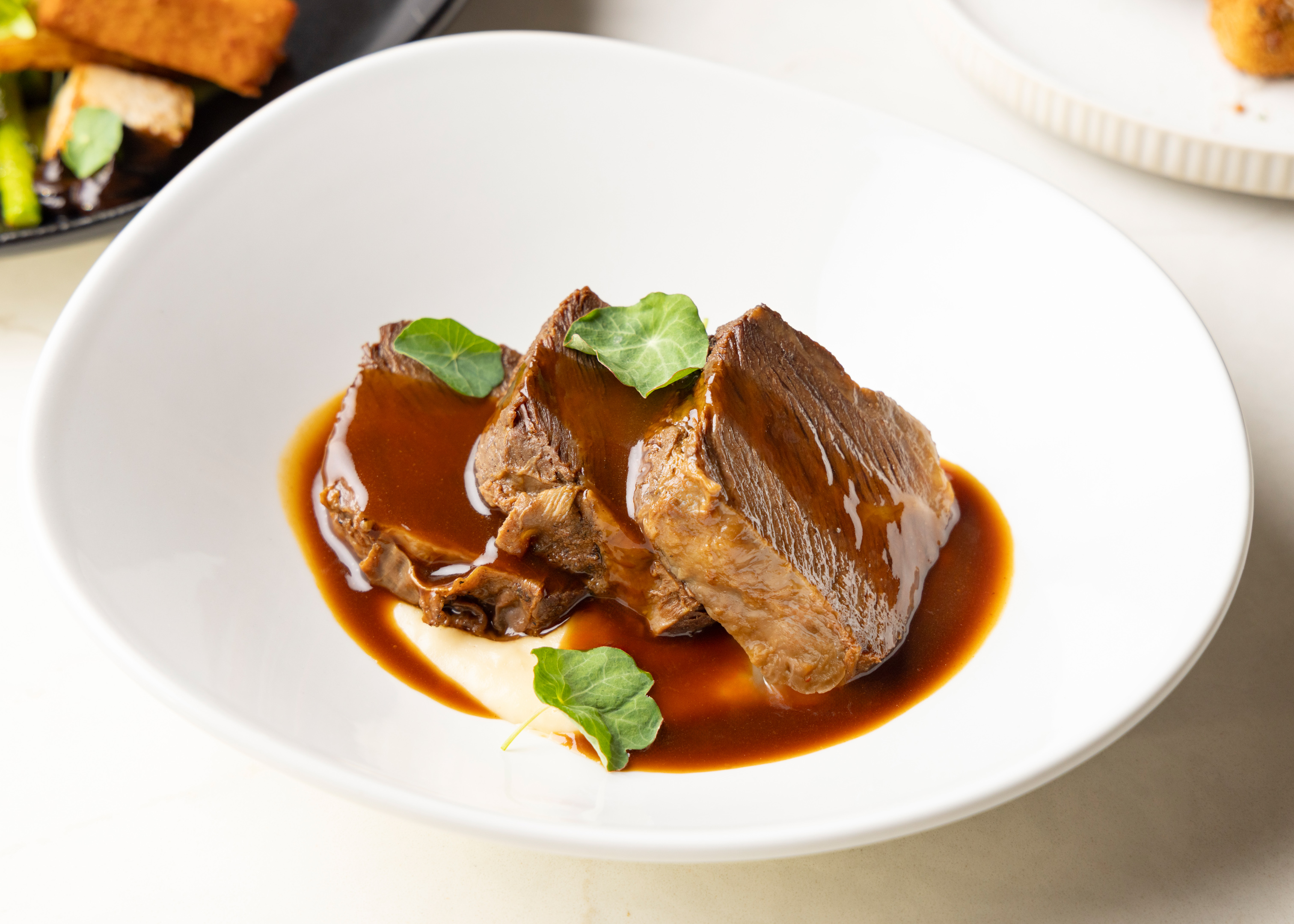 a plate of meat with gravy and green leaves