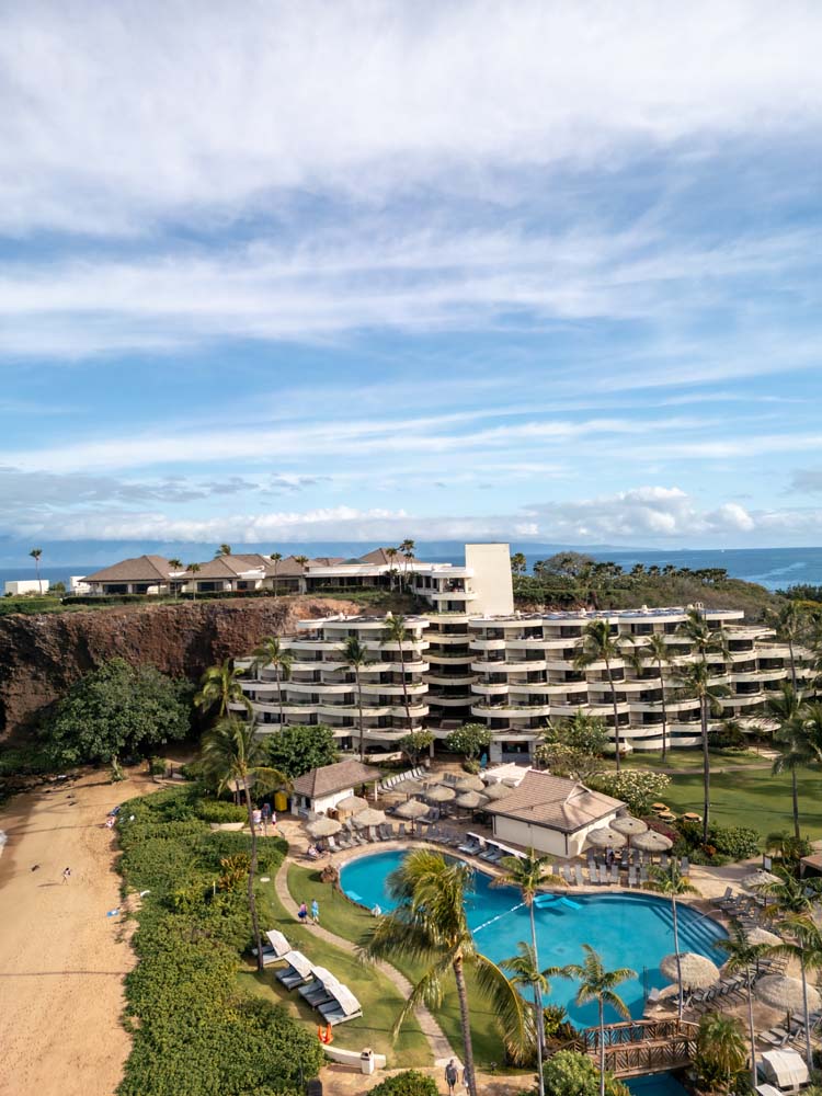 a swimming pool and a building with a beach and blue sky