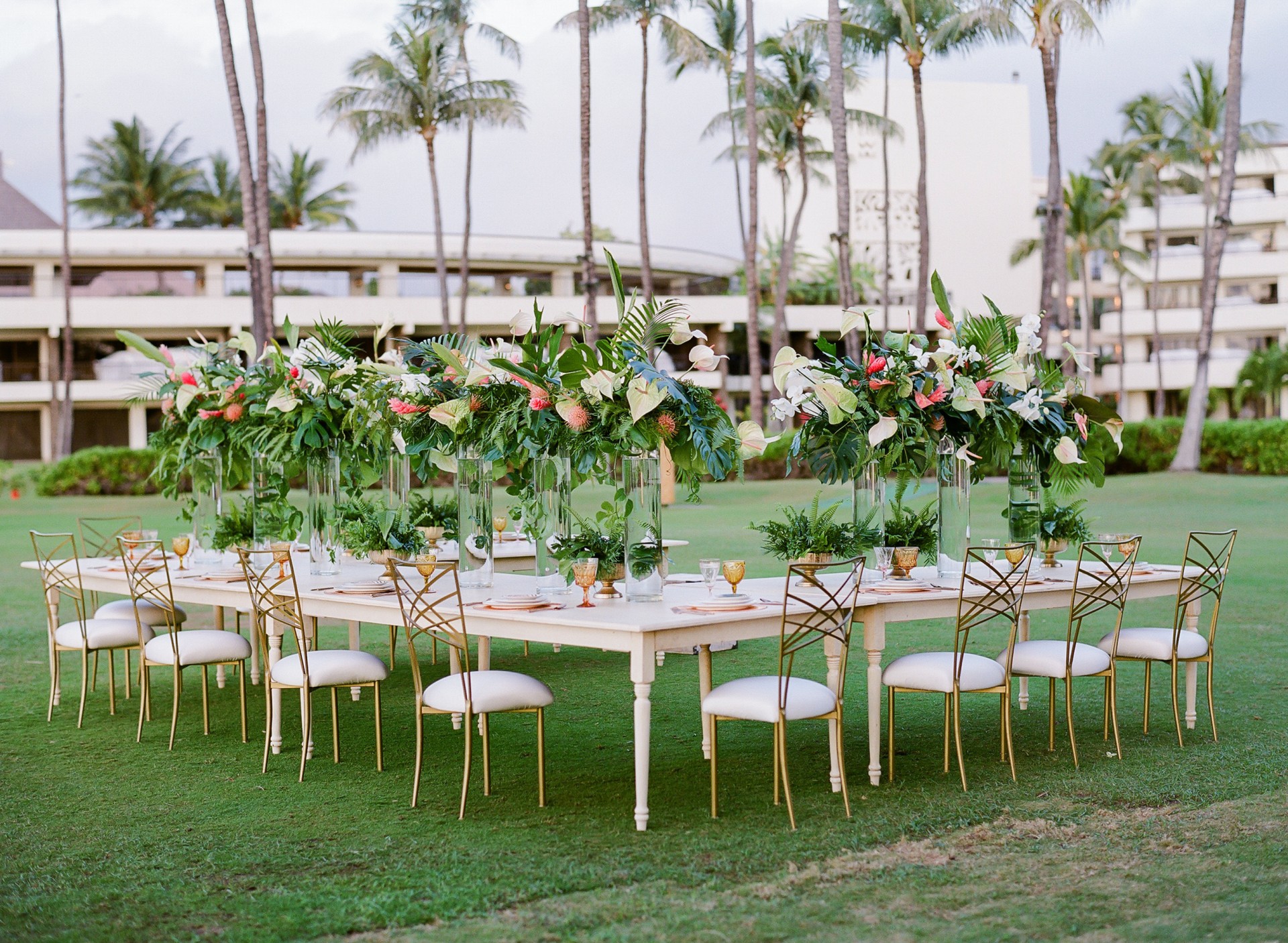 a table set up with flowers and chairs on grass