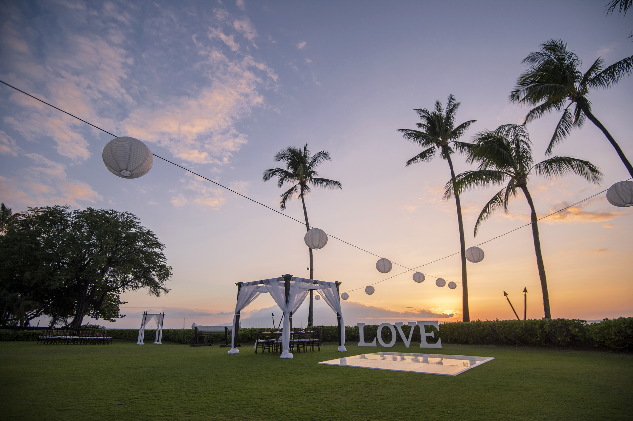 a wedding setting with palm trees and a sign
