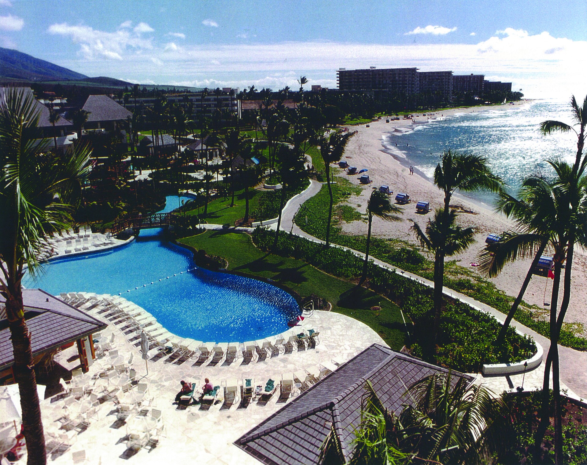 a swimming pool and beach with buildings and trees