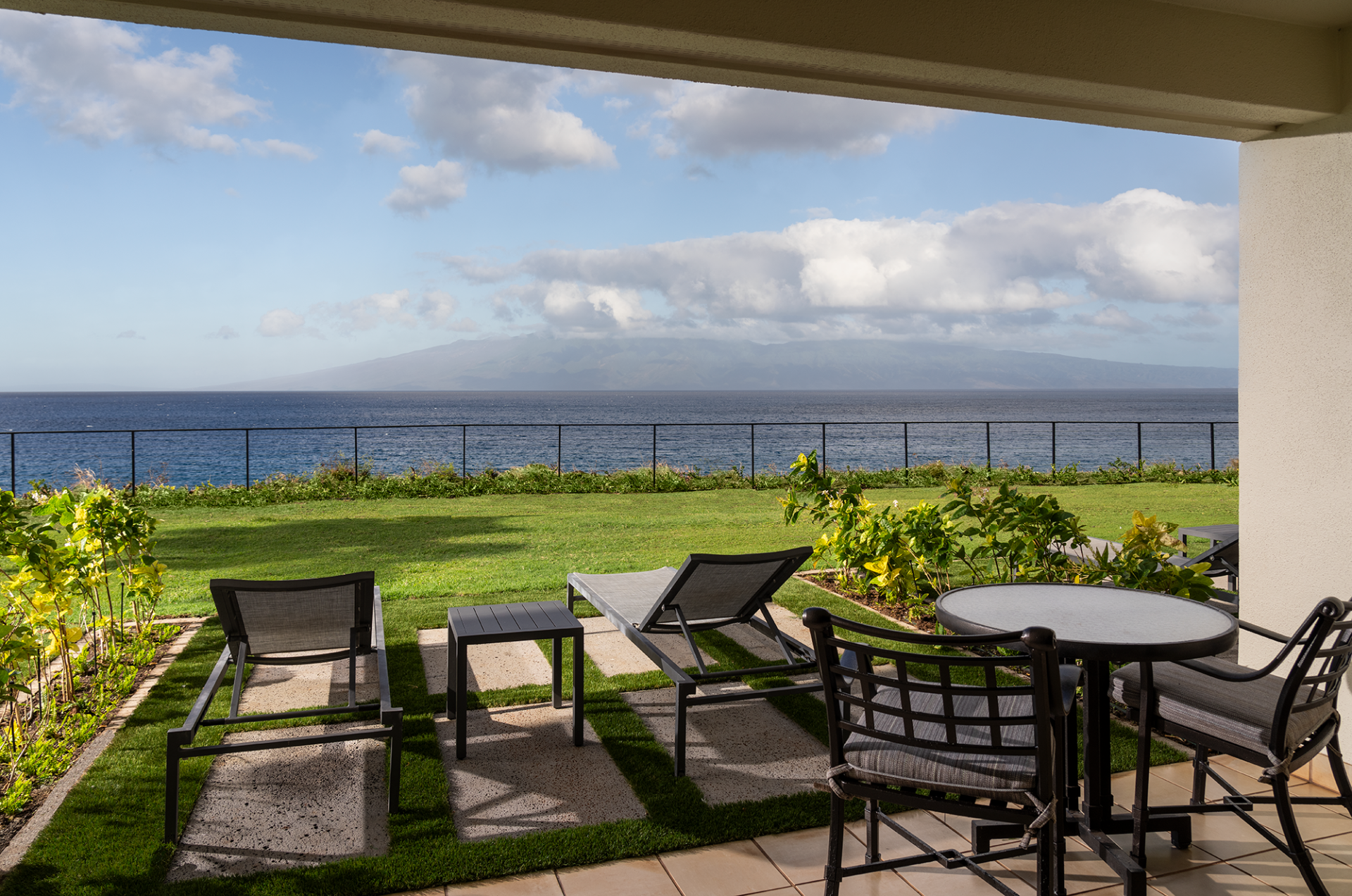 a patio with chairs and a table overlooking the ocean