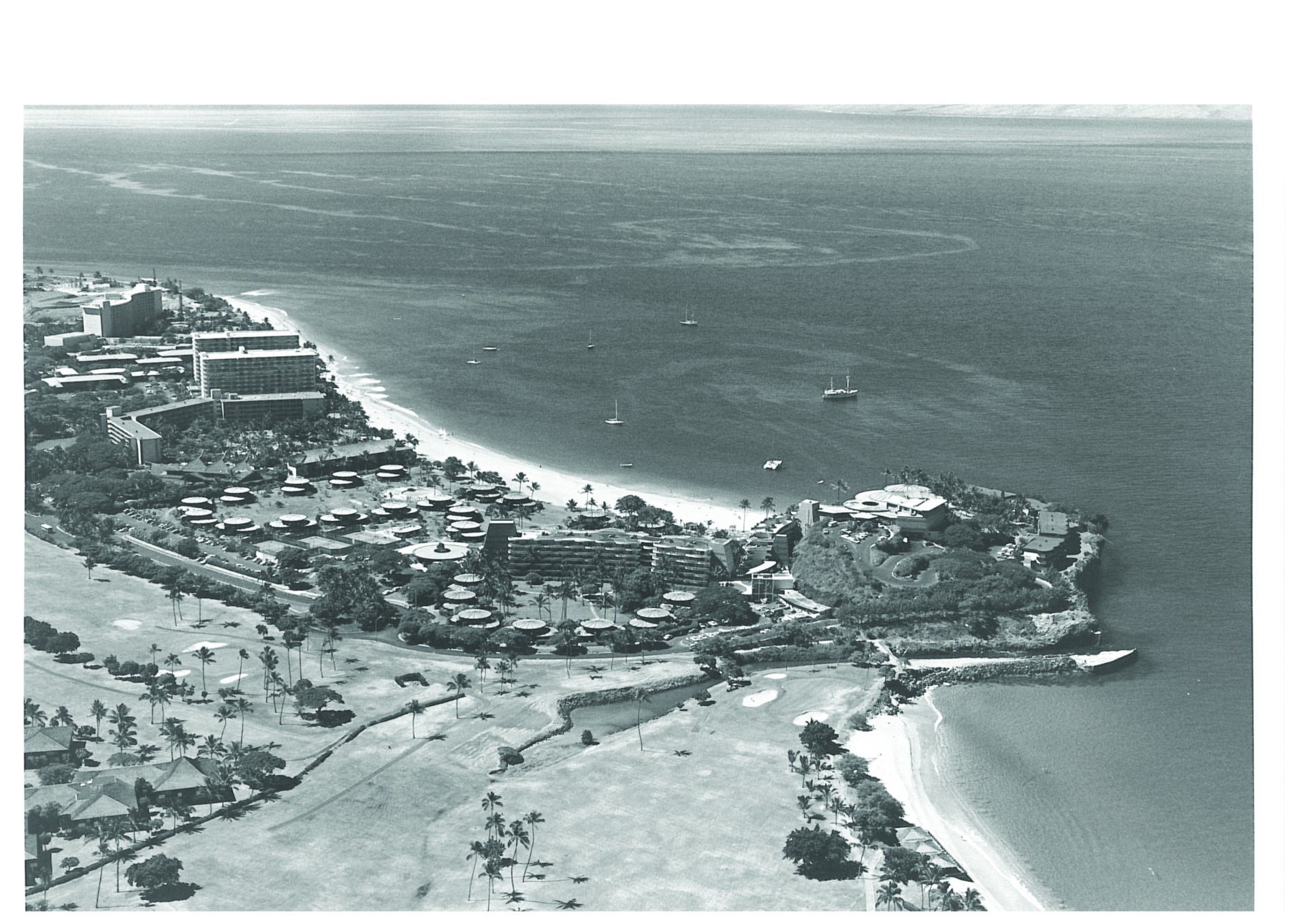 A historical black-and-white aerial photo capturing a tropical resort coastline, showing hotel buildings, circular cottage clusters, sandy beaches, and an adjacent golf course along the ocean.