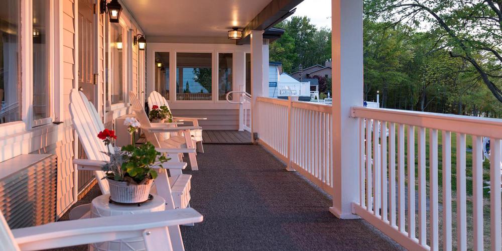 a porch with white chairs and a white railing