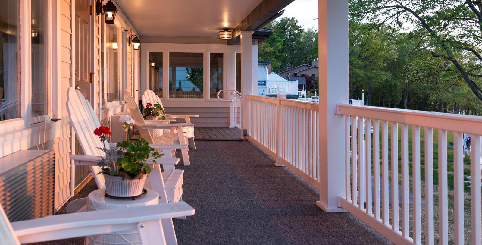 a porch with white chairs and a white railing
