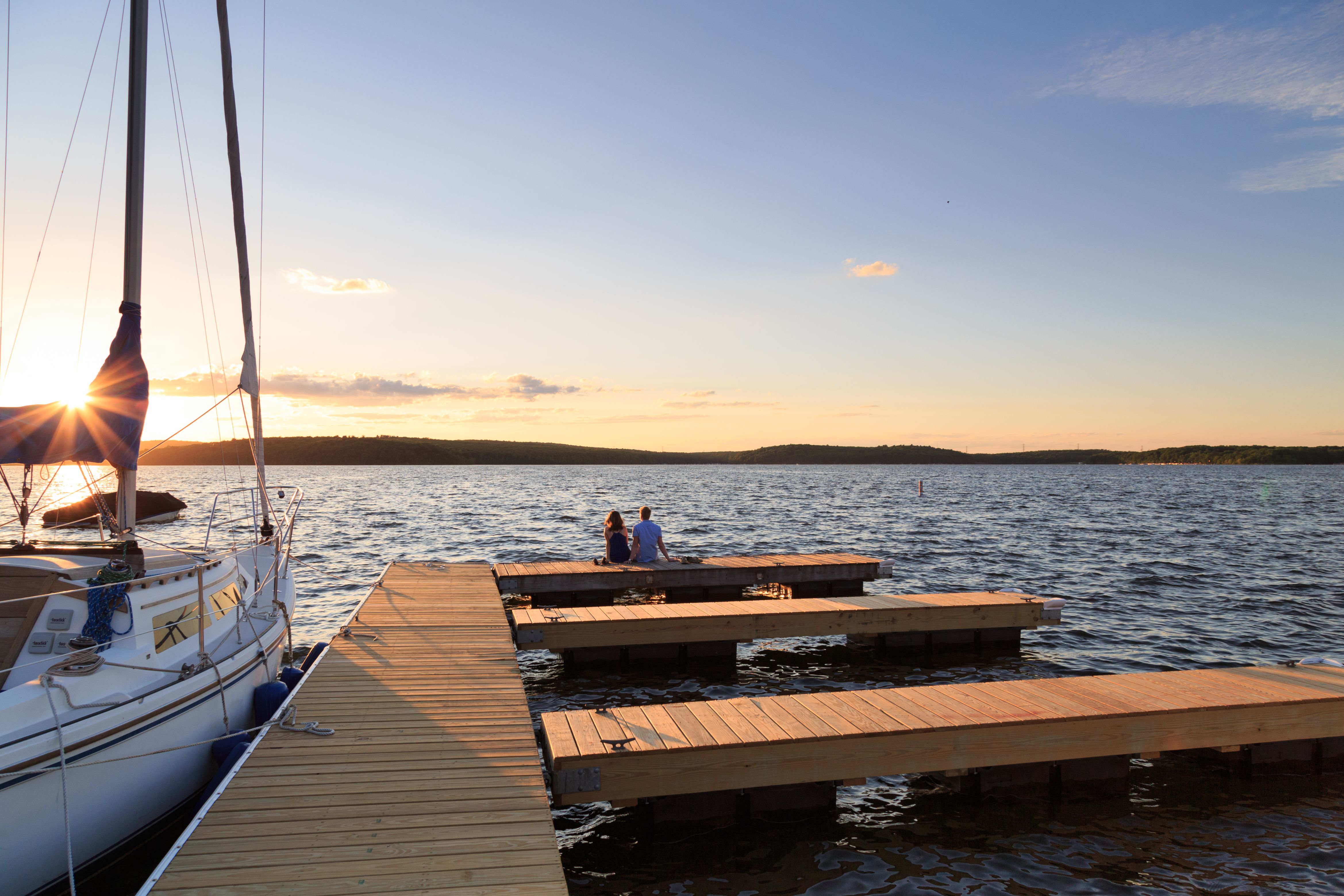 a couple sitting on a dock on a lake